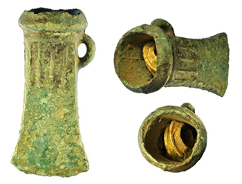 a bronze axe head from 3 different angles with a gold object inside the socket