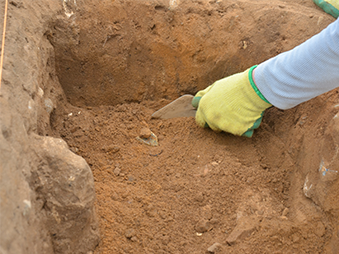 close up of trowel excavating in sandy soil