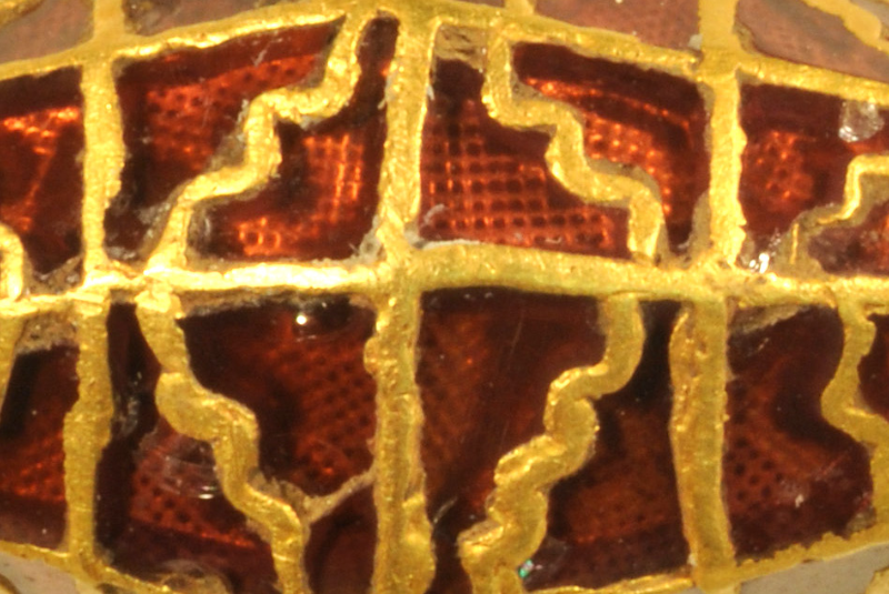 close up image of bead showing garnet overlaid by gold cloisonné work