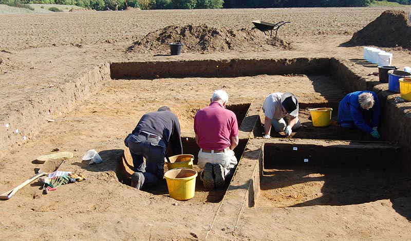 4 people excavating sections of a hut
