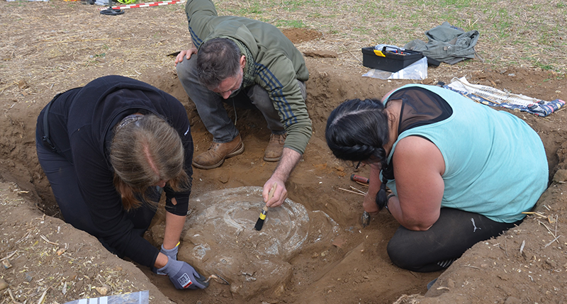 three people excavating pewter plate