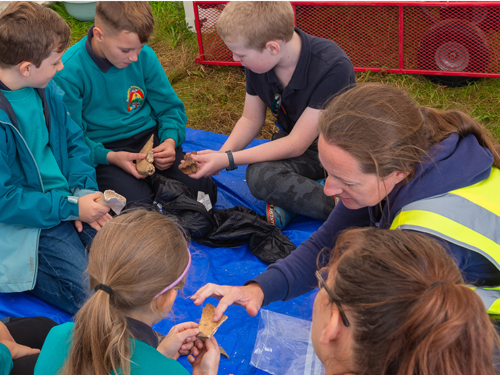 teacher and school children look at archaeological objects
