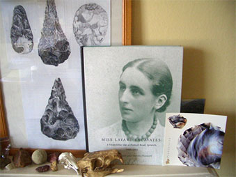 a collection of objects on a table, a framed photo of hand axes and a book about Layard