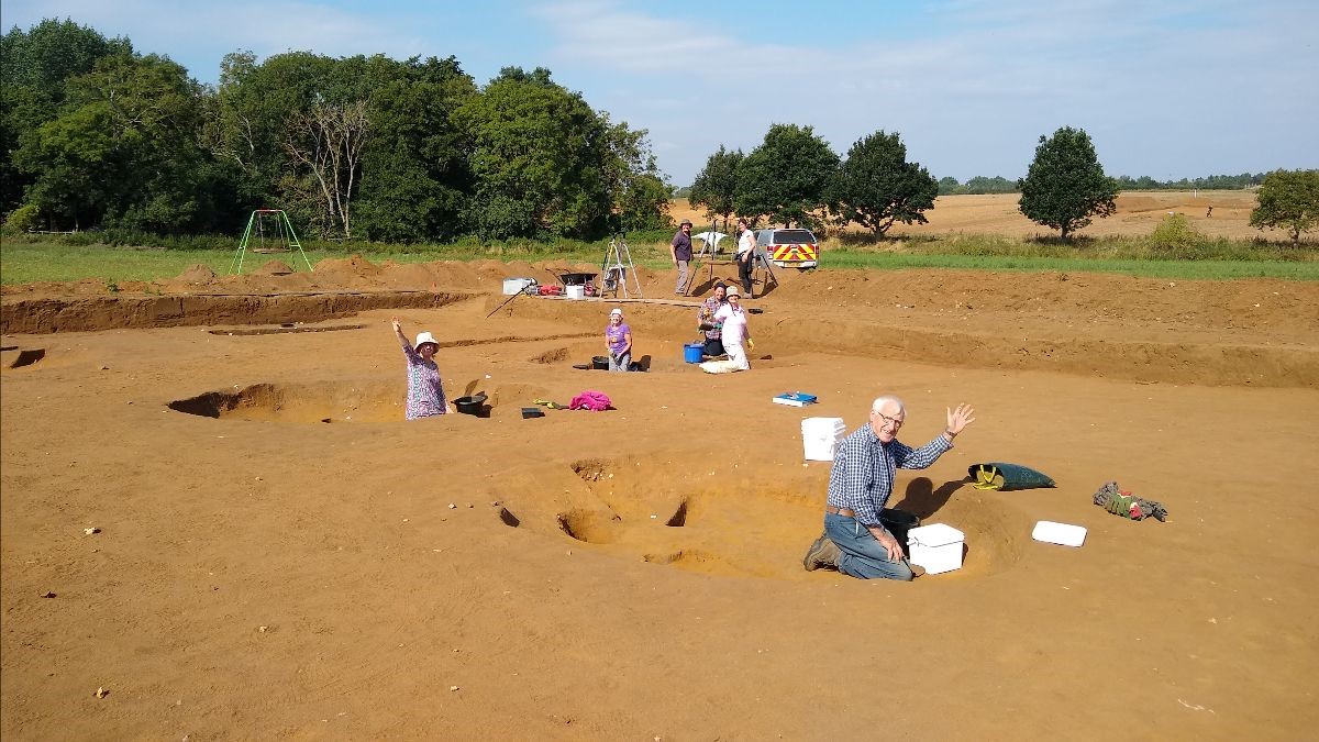 volunteers in trench waving