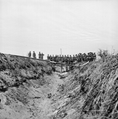 war photo of soldiers watching explosive device in trench
